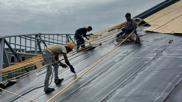 Applicators laying bituminous sheet membrane on a roof deck