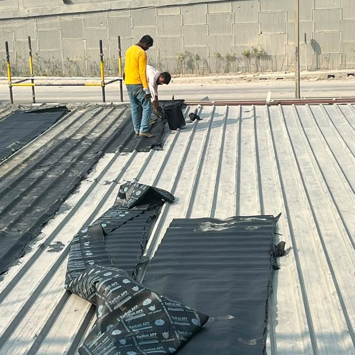 Membrane sheets being laid over a metal roof deck